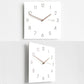 Two square wall clocks shown together, white faces with dark wood hands and numbers