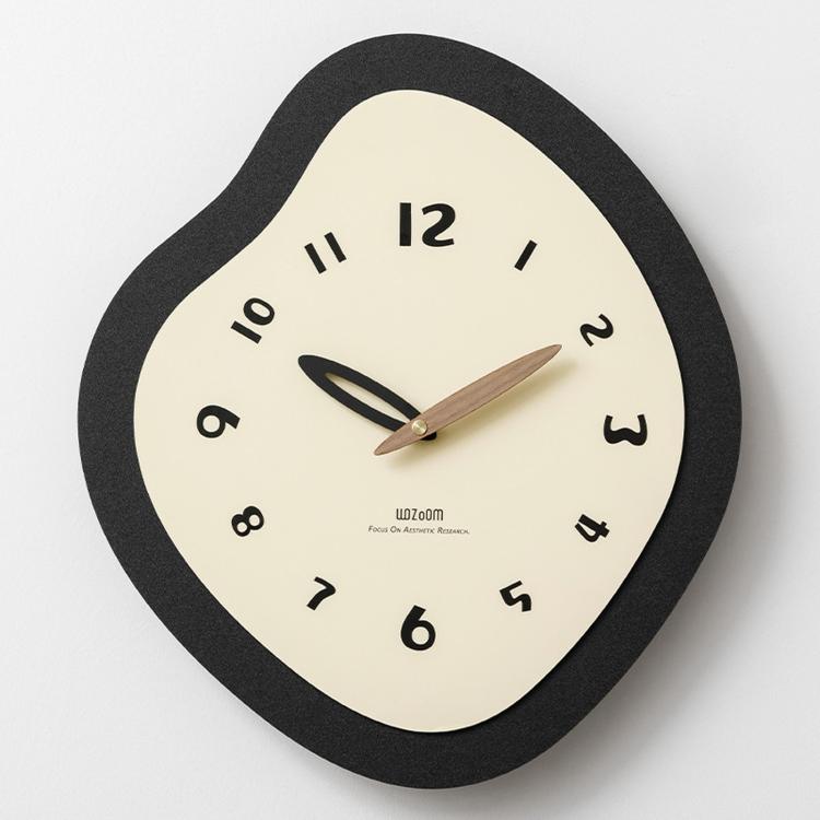 Irregular wall clock with black frame, cream face, and gold-toned clock hands.