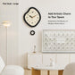 Irregular black wall clock with cream face, walnut hands, and gold tone hour markers
