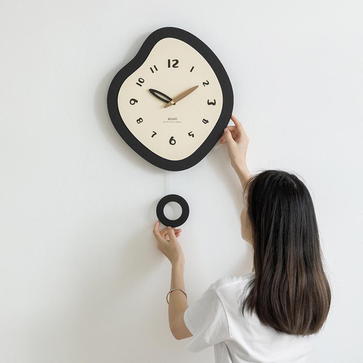 Irregular black wall clock with cream dial, walnut hands, and round mounting ring