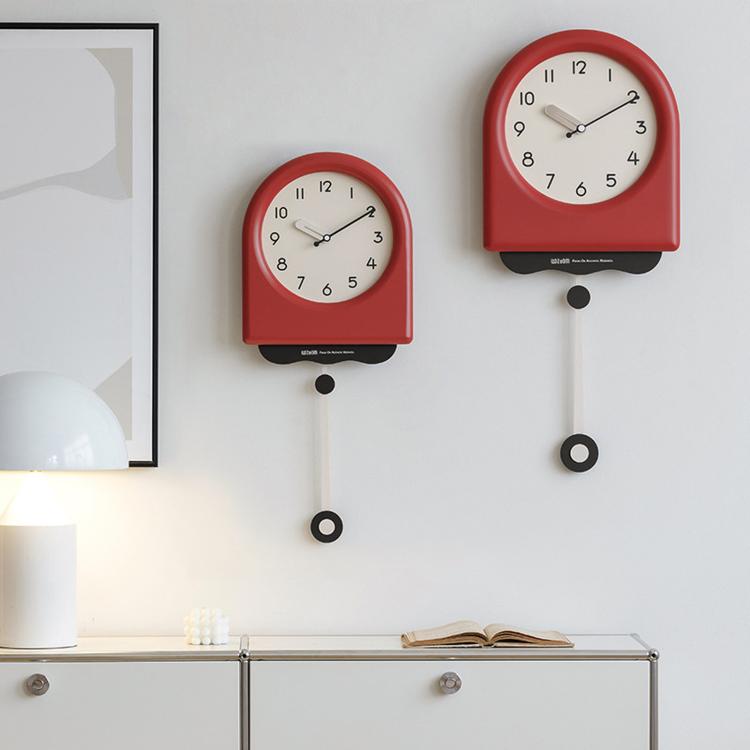 Set of two pendulum wall clocks with red and cream housings and hanging pendulum weights.