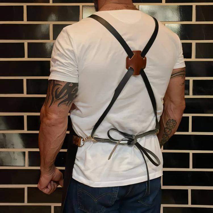 Black waterproof BBQ apron with cross-back straps and waist tie, worn on a model