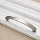 Curved brushed metal cabinet pull with smooth arch shape and two mounting end caps