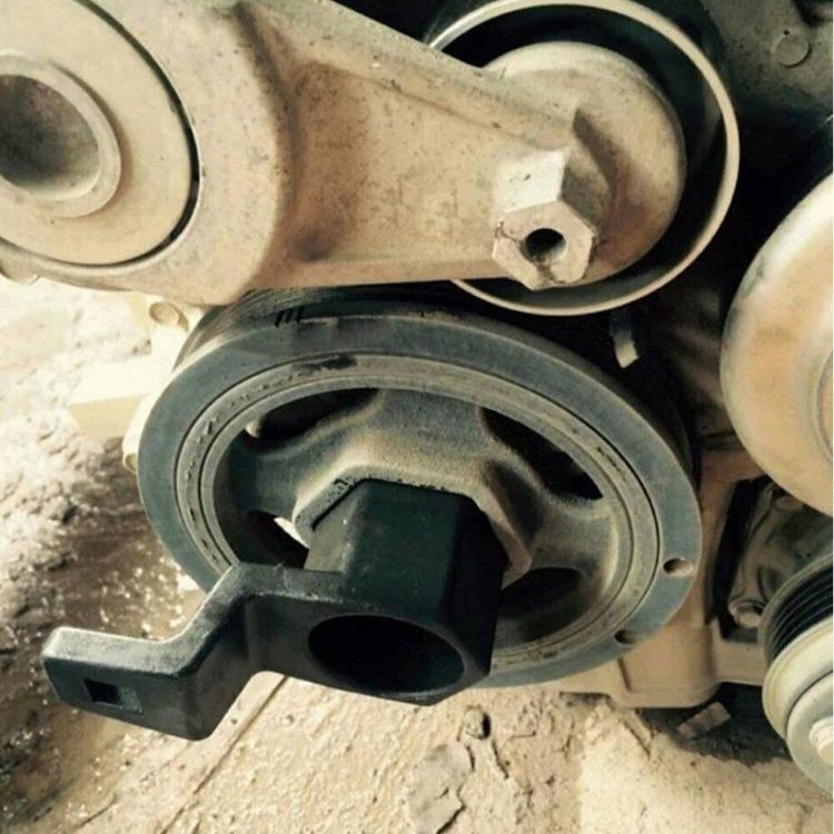 Black crankshaft belt pulley wrench fitted on crankshaft pulley