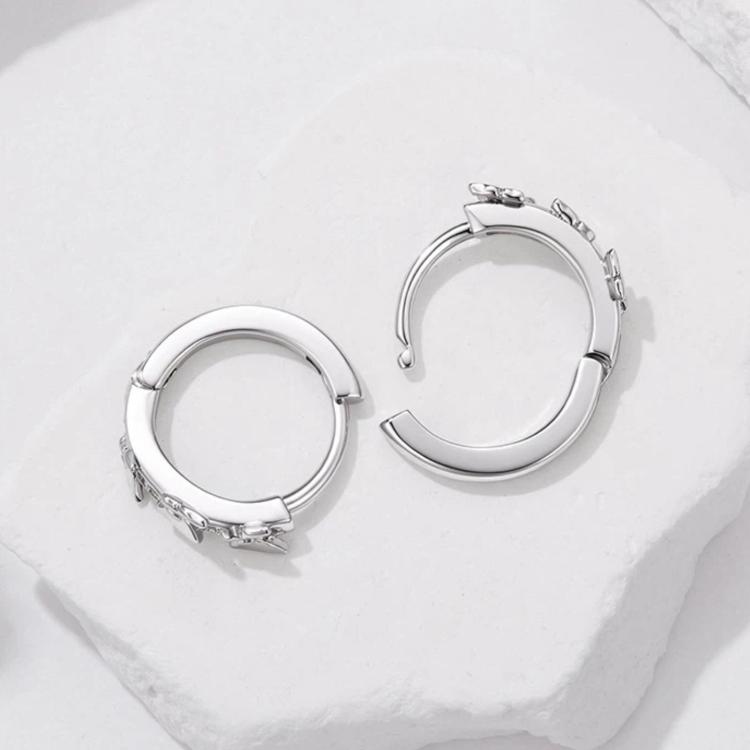 Close-up of silver-tone star and butterfly hoop earrings with clear rhinestones