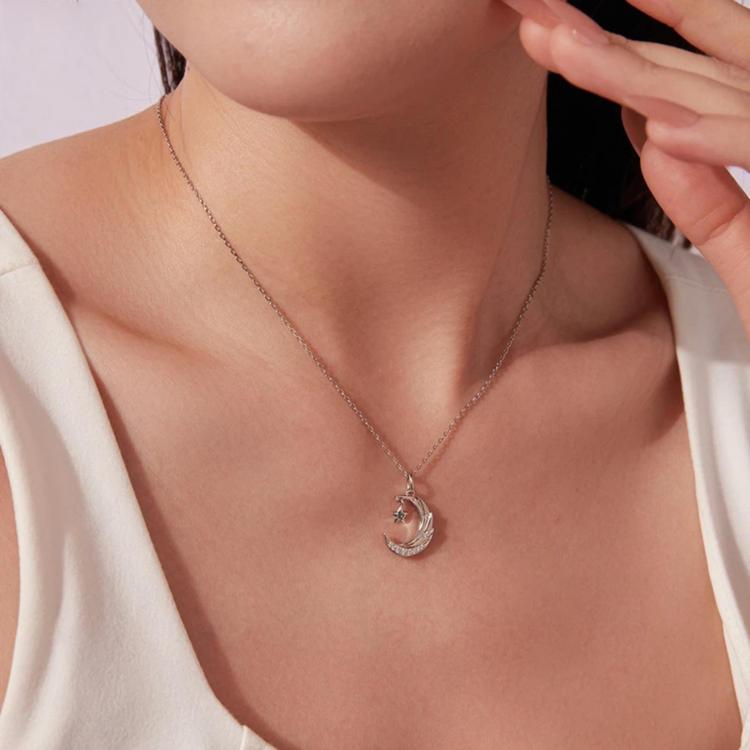 Crescent moon and star pendant necklace on a silver-tone chain, worn at neckline