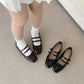 Women’s black ballet flats with two straps and buckles, worn with white ankle socks