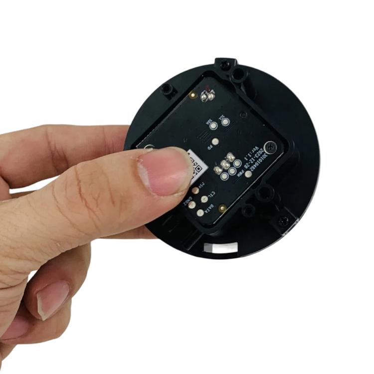 Exposed main control circuit board on black sensor module, held in hand