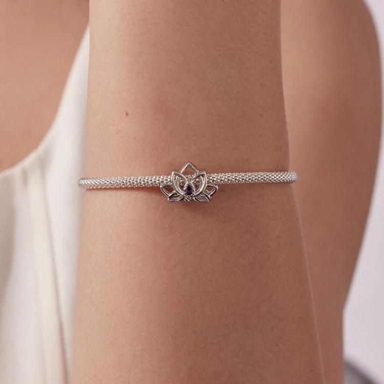 Lotus beaded bracelet on wrist, silver-toned chain with lotus charm and purple center