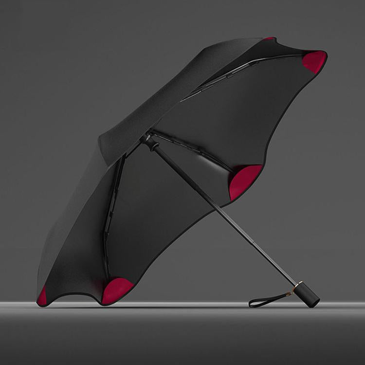 Three-fold manual sun umbrella, black canopy with red accents and curved frame ribs