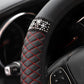 Close-up black quilted steering wheel cover with red diamond stitching and rhinestone band