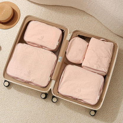 Pink packing cubes set in suitcase: four zippered organizer bags on wheels
