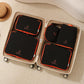 Black packing cubes set in suitcase: four zippered organizer bags with orange trim