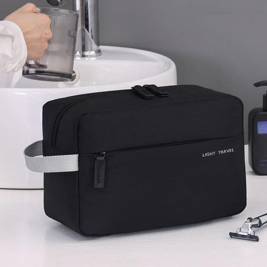 Black water-resistant mens toiletry bag with top flap and front zipper pocket