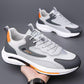 White gray breathable sneakers with lace-up closure and orange side accent on sole