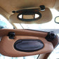 Black oval vanity mirror cover on car sun visor, installed on tan interior