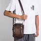 Brown leather crossbody bag worn by a man with adjustable shoulder strap