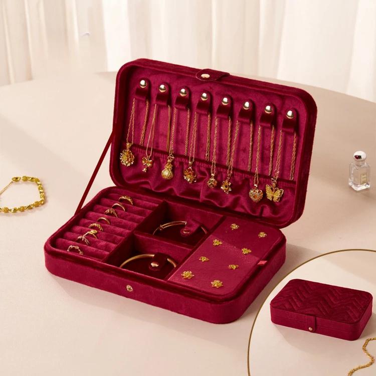 Dark red velvet jewelry box with open lid, earring hooks, and multi-slot compartments