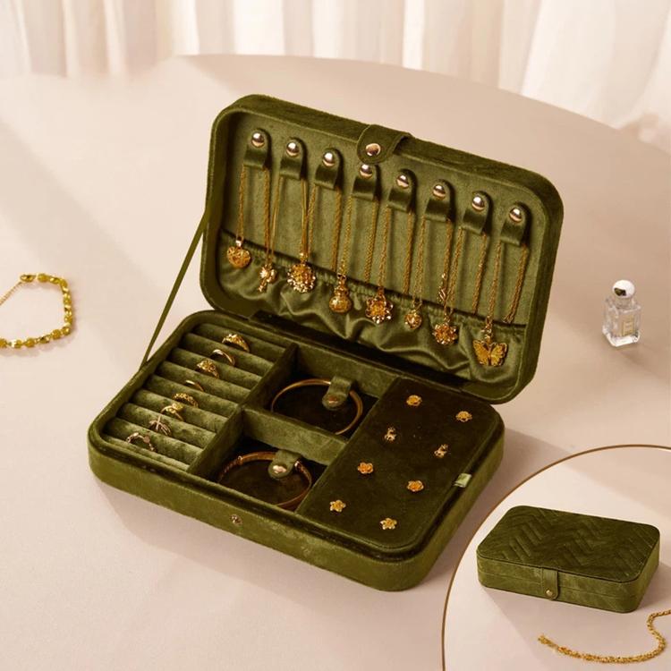 Emerald green velvet jewelry box with open lid, earring hooks, ring slots, and storage trays