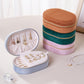 Stacked velvet oval jewelry cases in light blue, green, pink and brown with zippers
