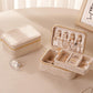 Cream beige velvet travel jewelry box with double zipper, open with earring and ring sections