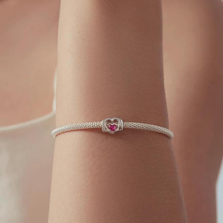 Sterling silver bracelet on wrist with small pink heart crystal bead charm
