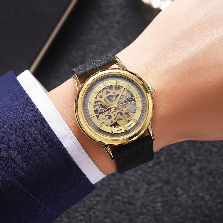 Gold-tone skeleton automatic watch with black leather strap on wrist