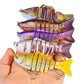 Hand holding assorted multi-segment hard fishing swimbait lures with treble hooks