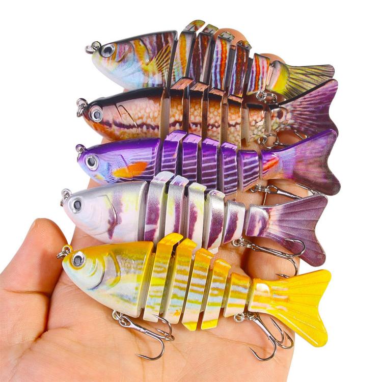 Hand holding assorted multi-segment hard fishing swimbait lures with treble hooks