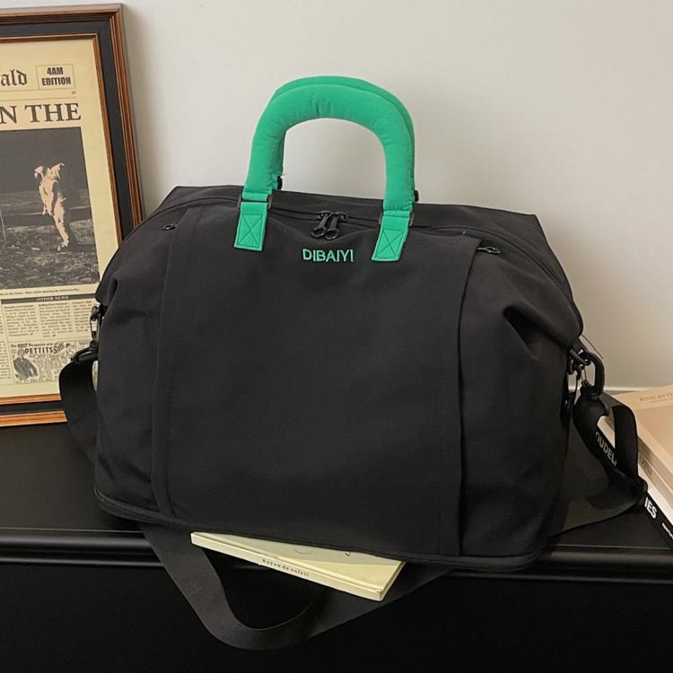 Expandable travel duffel bag in black with green padded top handles and shoulder strap