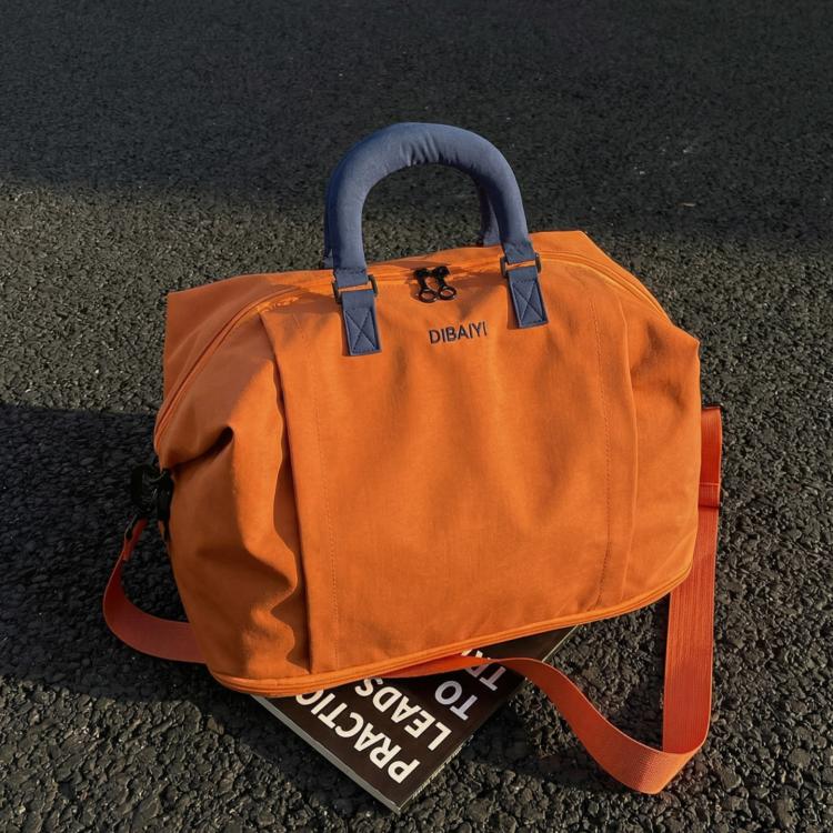 Expandable travel duffel bag in orange with blue top handles and two side straps