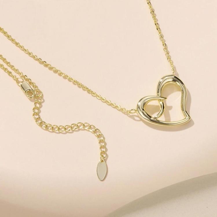 Gold-tone heart pendant necklace with infinity detail, close-up on chain