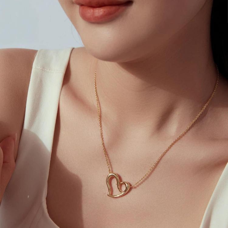 Gold-tone heart pendant necklace worn with cable chain on neckline