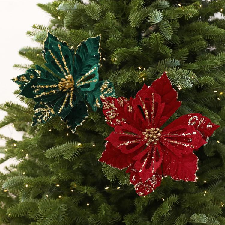 Artificial poinsettia flower decorations in dark green and red on a Christmas tree