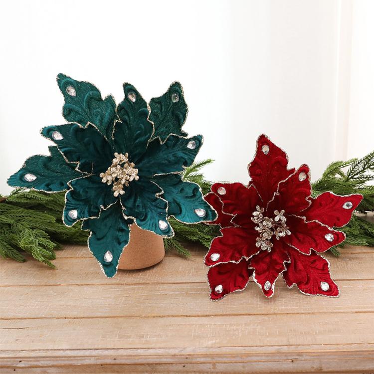 Teal and wine red velvet poinsettia ornaments on a wooden surface