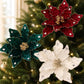 Velvet poinsettia ornaments in teal, red, and white on a decorated Christmas tree