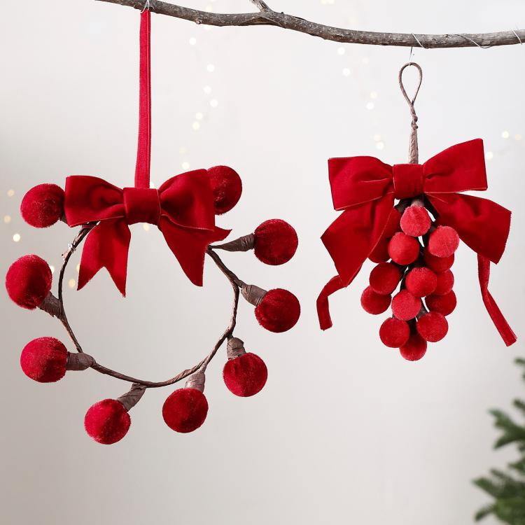 Red pom-berry wreath ornament pair with ribbon bows, hanging on branch