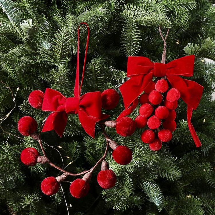 Red ribbon bow pom-berry grape-cluster wreath ornament hanging on fir