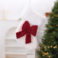 White fluffy hanging stocking ornament with red fabric bow at the cuff