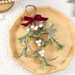Artificial mistletoe ornament with red velvet bow and white bead berries on frosted greenery