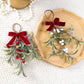 Artificial mistletoe hanging ornaments on a tray: one red-berry, one white-berry, red velvet bows