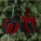 Two hanging velvet gift box ornaments on a Christmas tree with ribbon bows