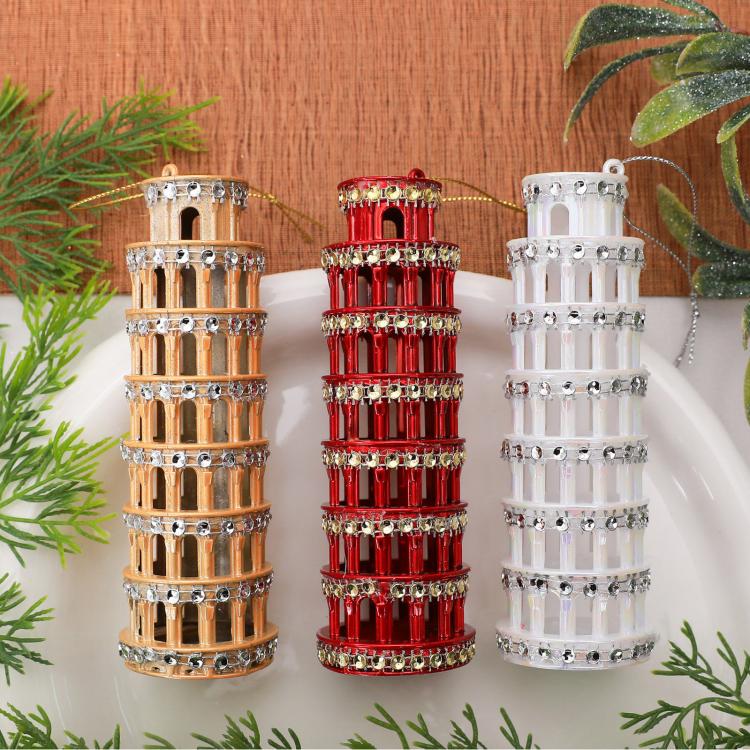 Diamond-studded leaning tower ornaments in gold, red, and white on a tabletop