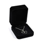 Black octagonal velvet jewelry box, open with heart-and-cross pendant necklace