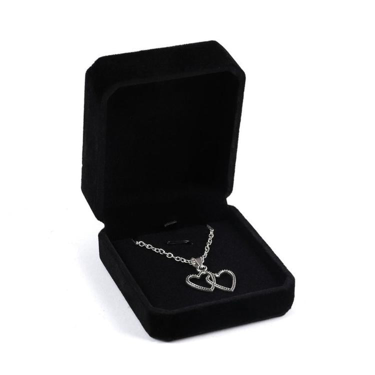 Black octagonal velvet jewelry box, open with heart-and-cross pendant necklace