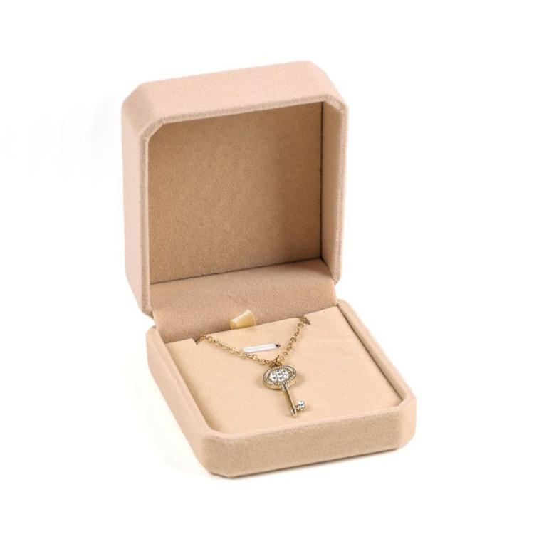 Beige octagonal velvet jewelry box, open with gold-tone cross pendant necklace