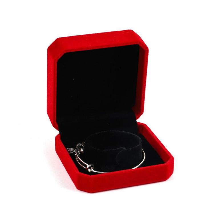 Red octagonal velvet jewelry box with open lid and black ring/bracelet display