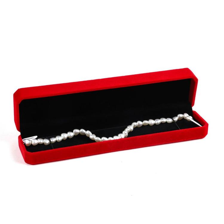 Red octagonal velvet jewelry box with open lid holding a white pearl bracelet