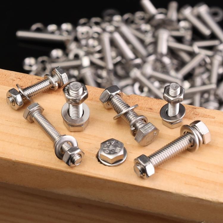 Stainless steel hex bolts and nuts scattered on a wooden board, mixed sizes