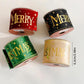 Four Christmas ribbon rolls: red “Merry”, black “Merry”, green “S T M A S”, gold “S T M A S”